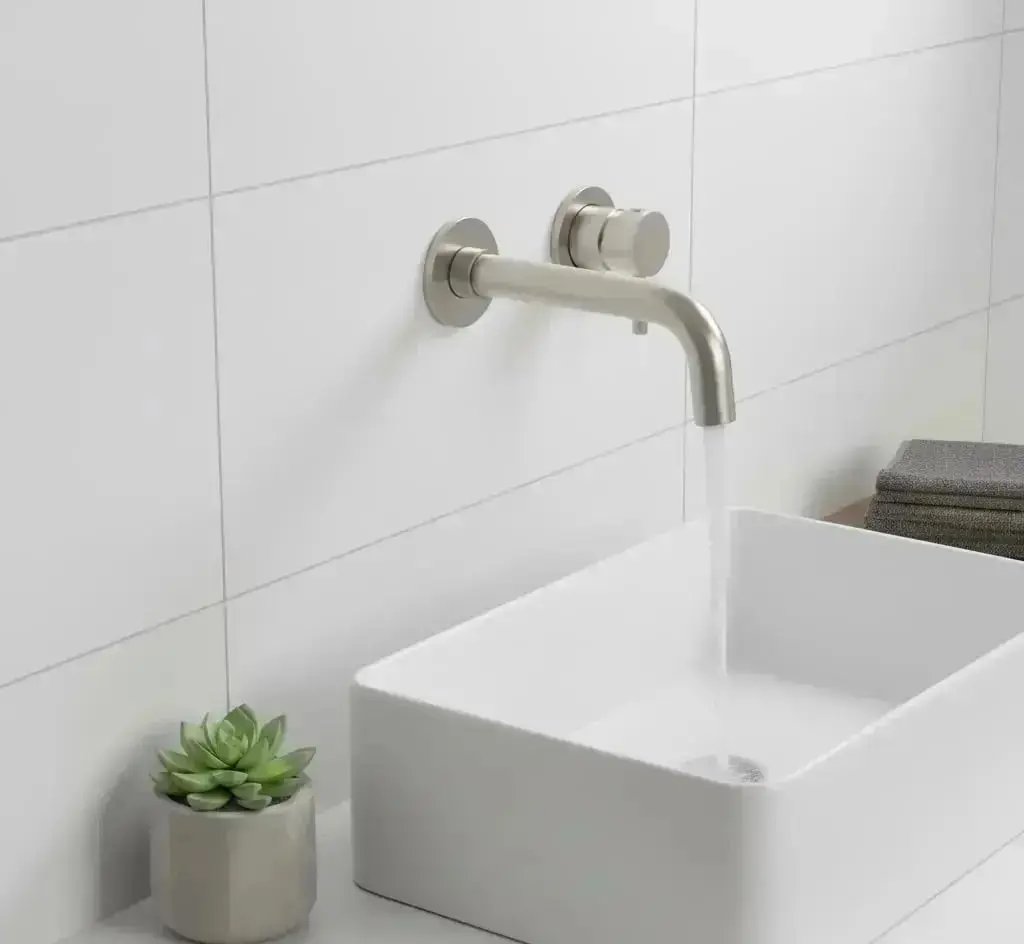 Moderne badkamer met Stria inbouw wastafelmengkraan afbouwdeel in geborsteld RVS, gemonteerd boven een witte rechthoekige opbouw wasbak op een houten plank, met de kraan geopend en water stromend.